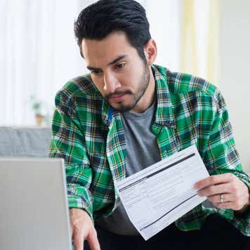 Mixed race man paying bills in living room
