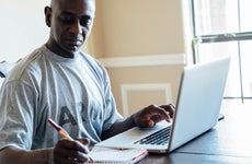 A Black army veteran jots notes while using a laptop.