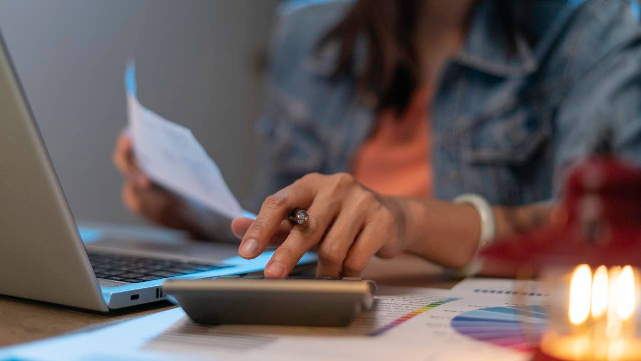 Close up of woman planning home budget and using calculator.