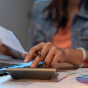 Close up of woman planning home budget and using calculator.