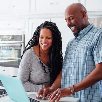 Man and woman using laptop in kitchen at home