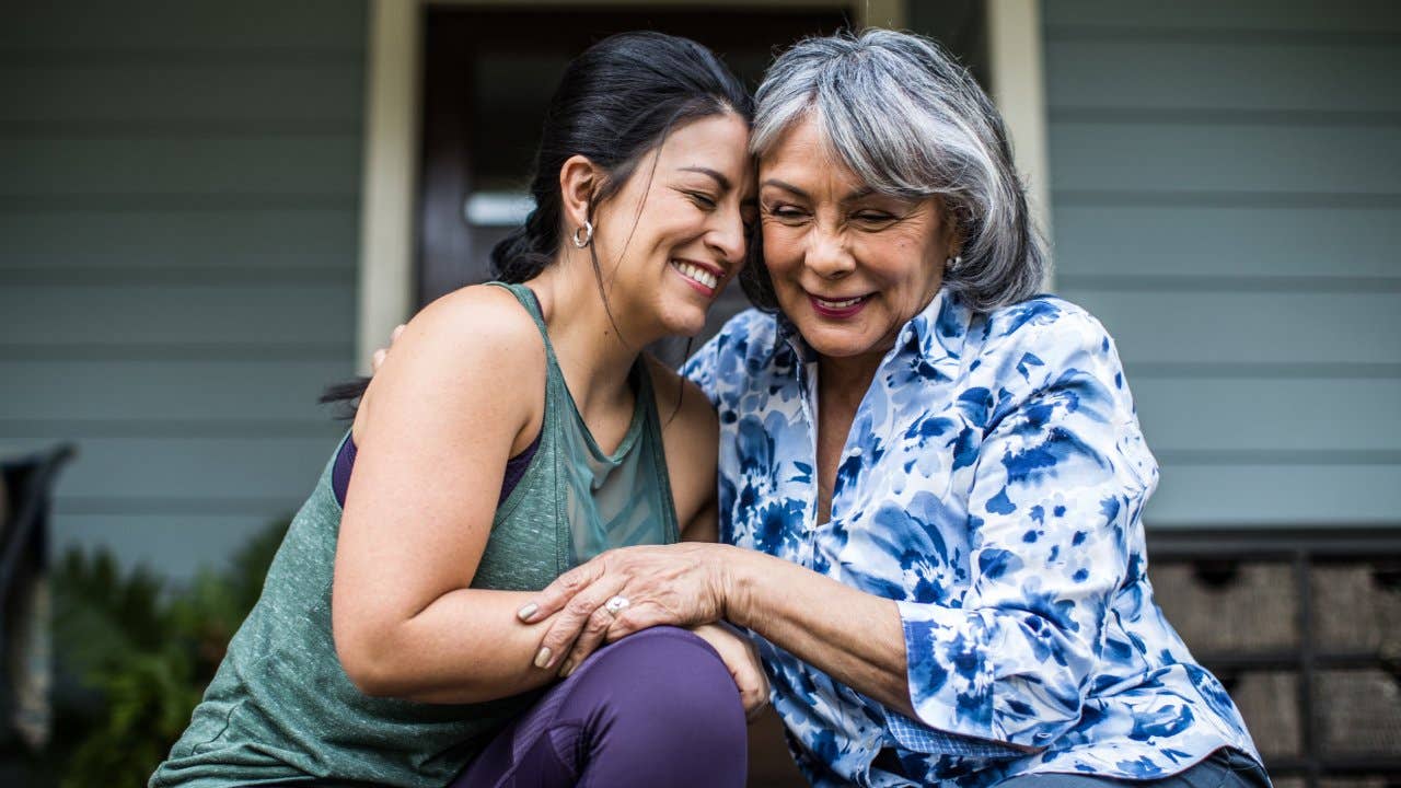 Senior woman and adult daughter laughing on porch