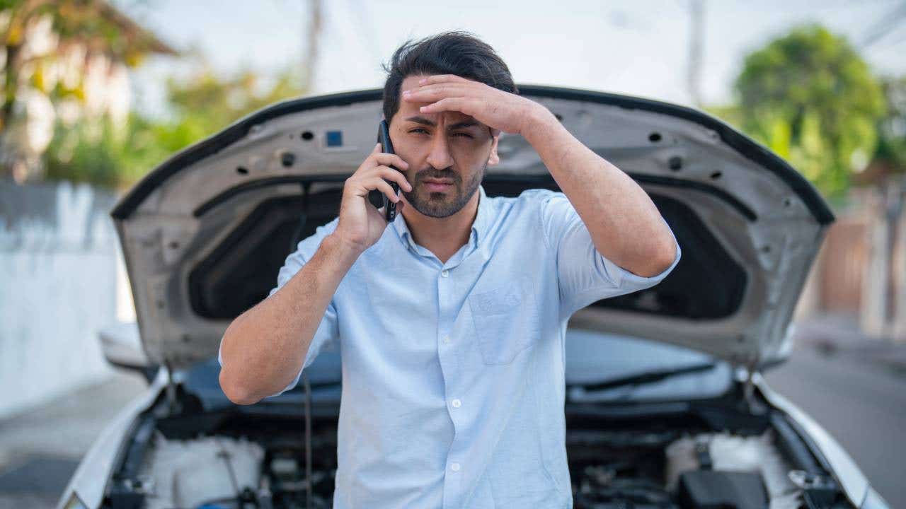 Man calling assistance after car breakdown