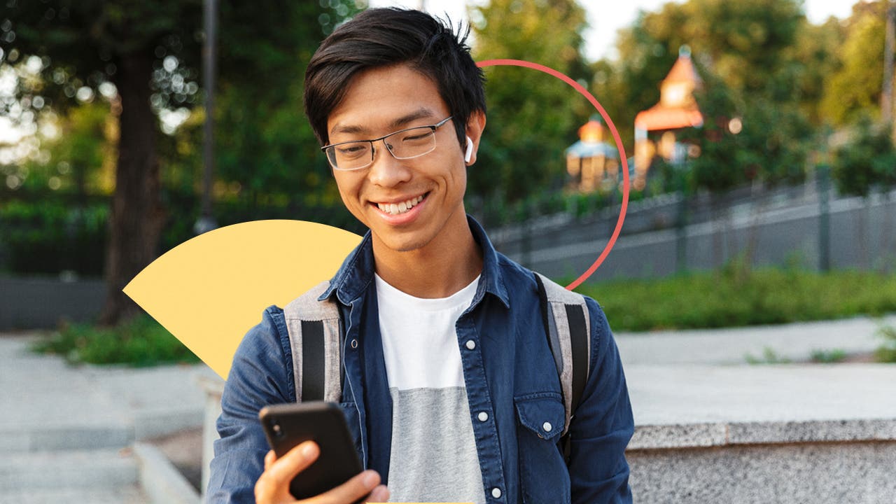 Image of a high school student checking his phone on school campus