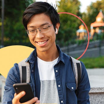 Image of a high school student checking his phone on school campus