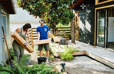 Couple carrying lumber to build raised garden beds in backyard