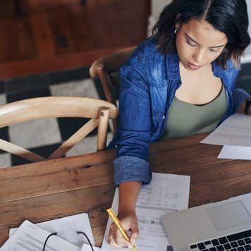 woman using a laptop and going through paperwork while working from home