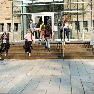 Multi-ethnic group of students in front of College University entrance.