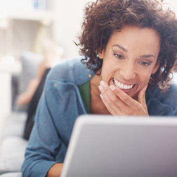 Smiling woman using laptop on sofa