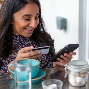 Smiling woman making online payment with credit card in cafe