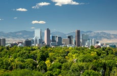 The towering high rises of Denver's downtown sit between the Front Range of the Rocky Mountains to the west and the tree lined neighborhoods and parks of the city to the east.