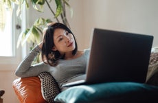 Young pregnant businesswoman at home office, working with laptop on sofa