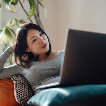 Young pregnant businesswoman at home office, working with laptop on sofa