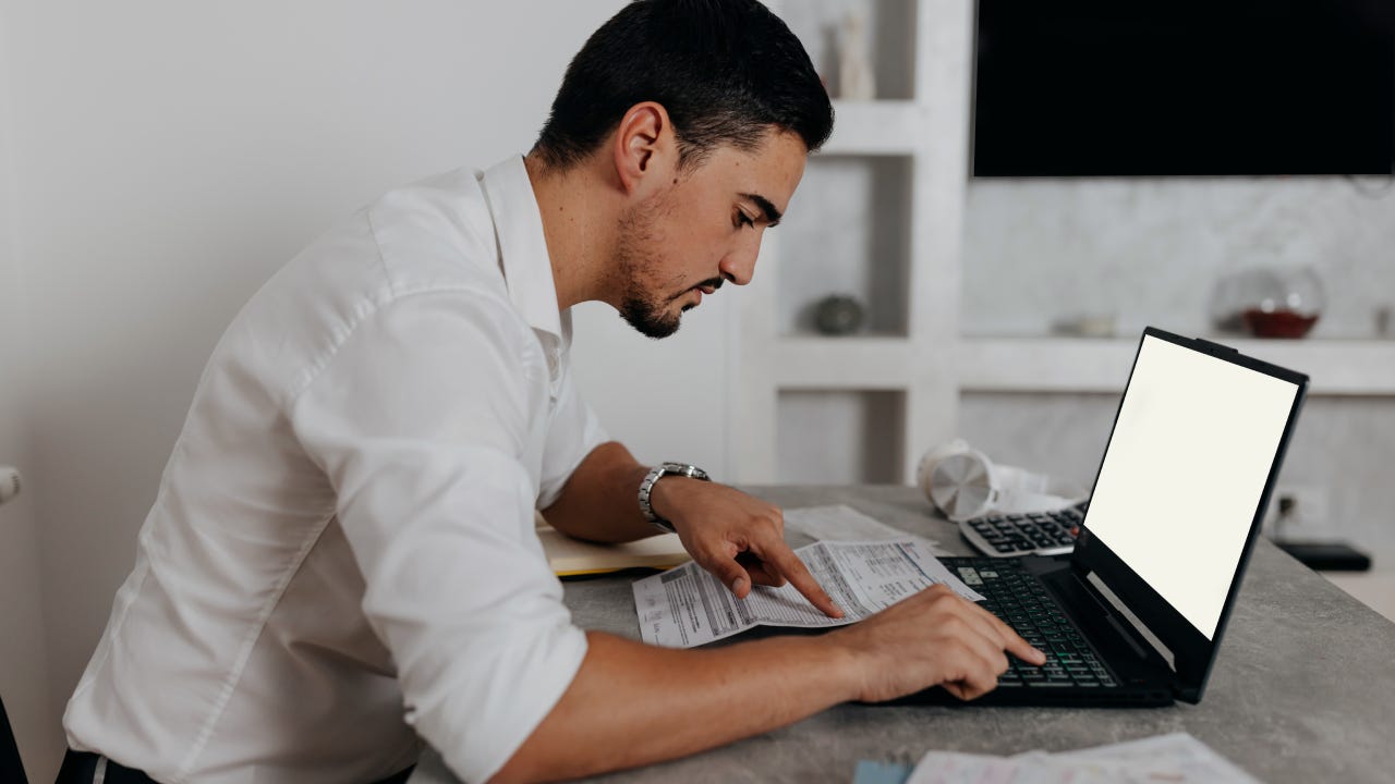 A serious Caucasian man paying bills online