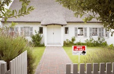 House with for sale sign in yard and open wooden fence