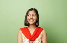 South asian woman looking to side against green background