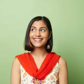 South asian woman looking to side against green background