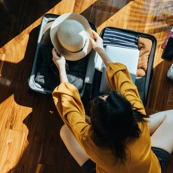 Overhead view of young Asian woman packing a suitcase for a trip