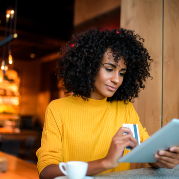 Beautiful smiling African American woman using digital tablet at the bar.