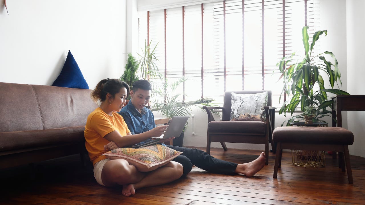 Young couple sitting on the floor at home with a laptop