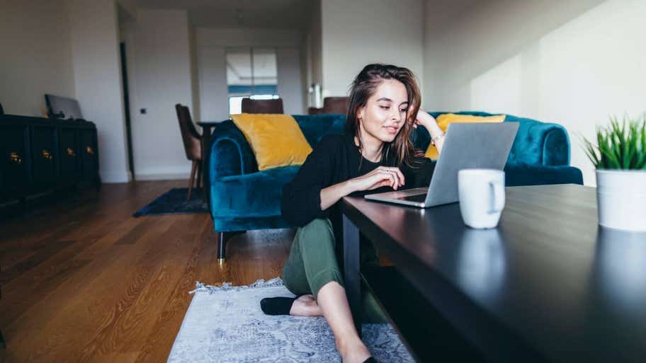 A young woman is using a laptop at home.