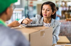 A woman signs or delivery of a package in a business.