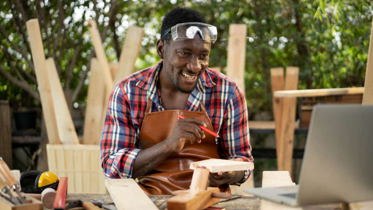 A Black carpenter holds a piece of wood.