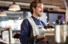 A smiling coffeehouse barista prepares a drink