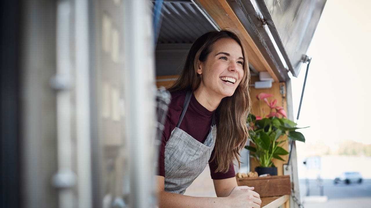 A smiling woman looks out from her food truck.
