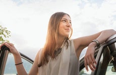Confident woman leaning at her new car