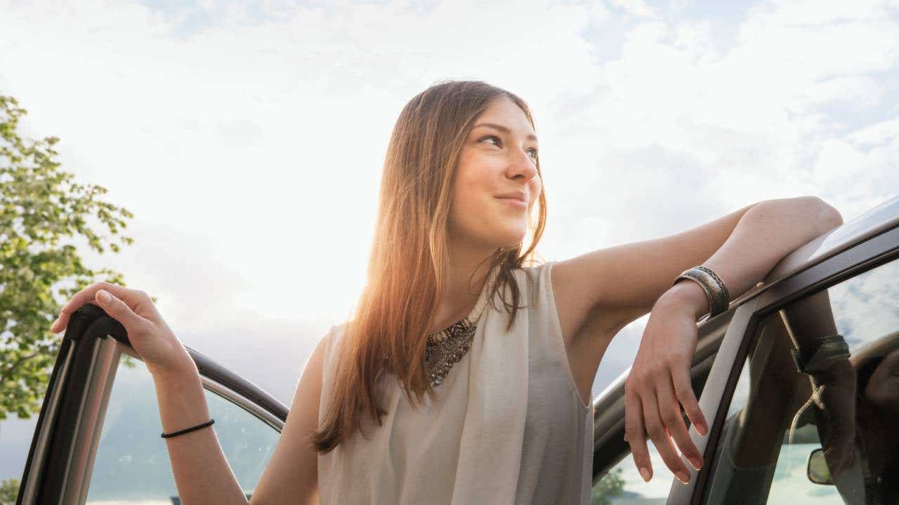 Confident woman leaning at her new car
