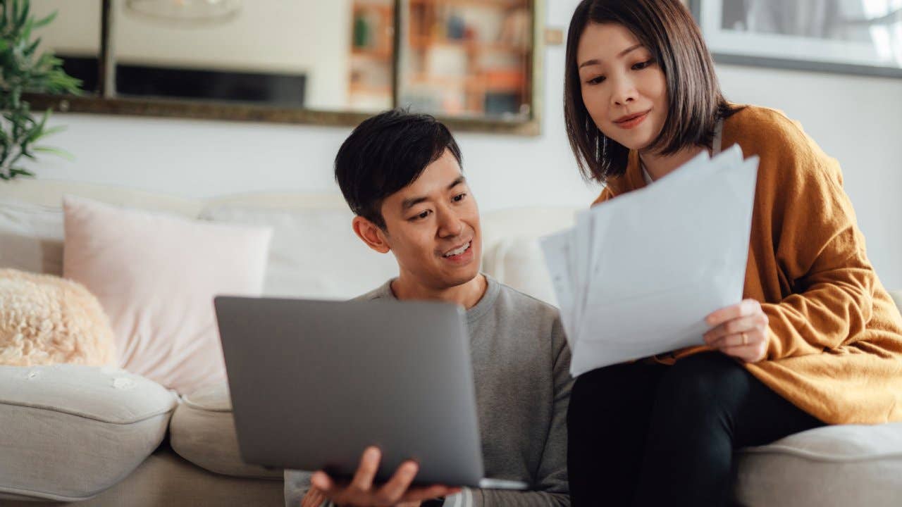 Young couple discussing over financial bills while using laptop on sofa