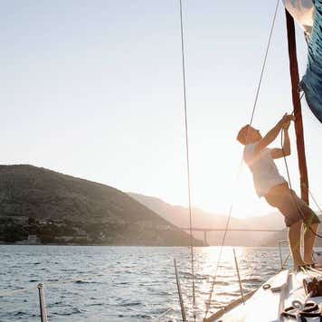 Man hoisting sail, backlit
