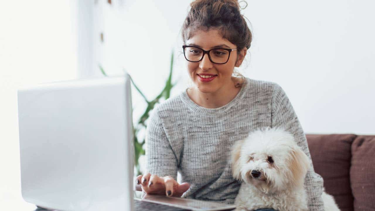 Young woman working at home with her dog.