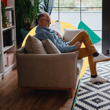 An old person sitting on a couch looking at their phone
