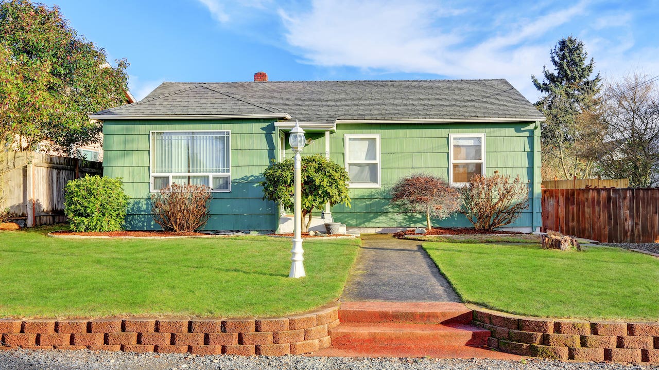 government sponsored enterprise - green bungalow style house with landscaping and blue sky and white lamppost