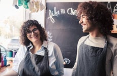 Male and female co-owners work together in aprons at a shop.