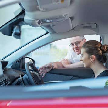 Salesman demonstrating car controls to customer in car dealership