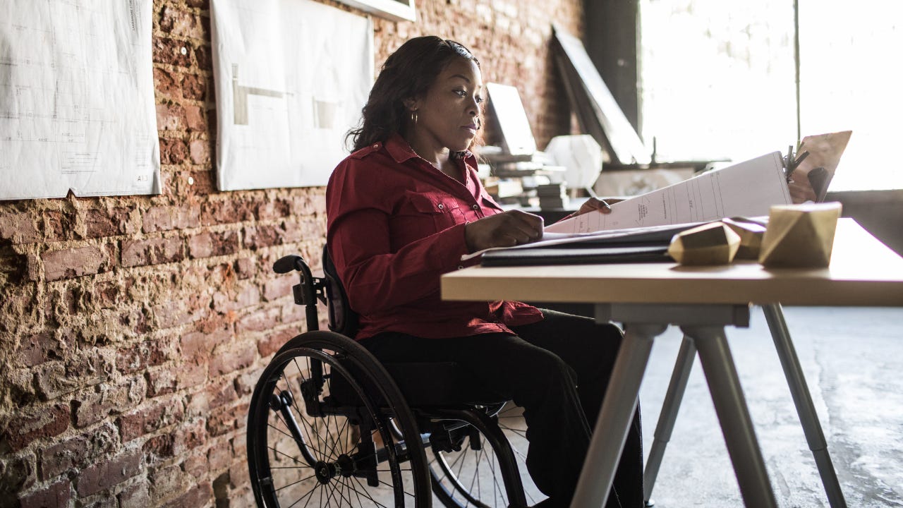 A businesswoman in a wheelchair works at her desk.
