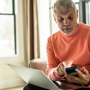Senior man using laptop computer and smartphone at home
