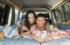 Two young women inside camper van taking selfie