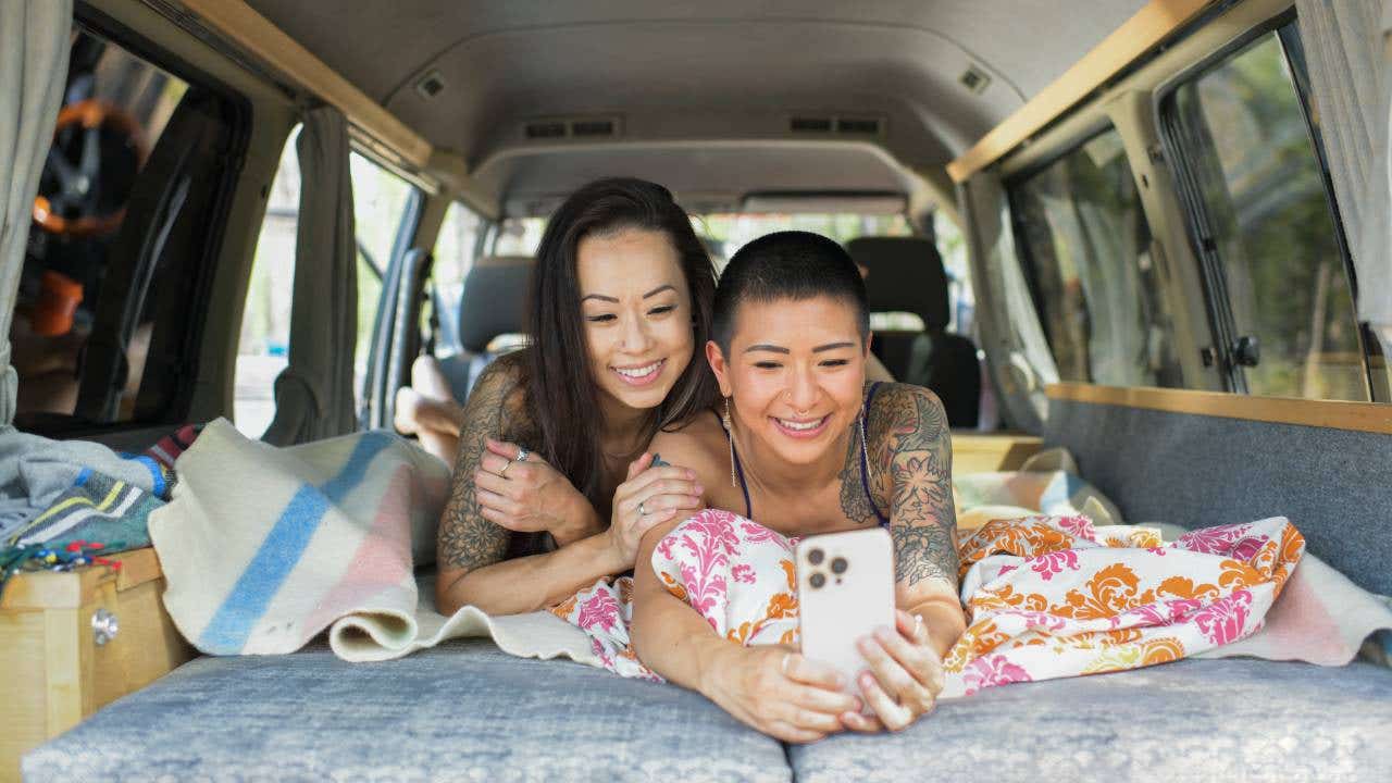Two young women inside camper van taking selfie