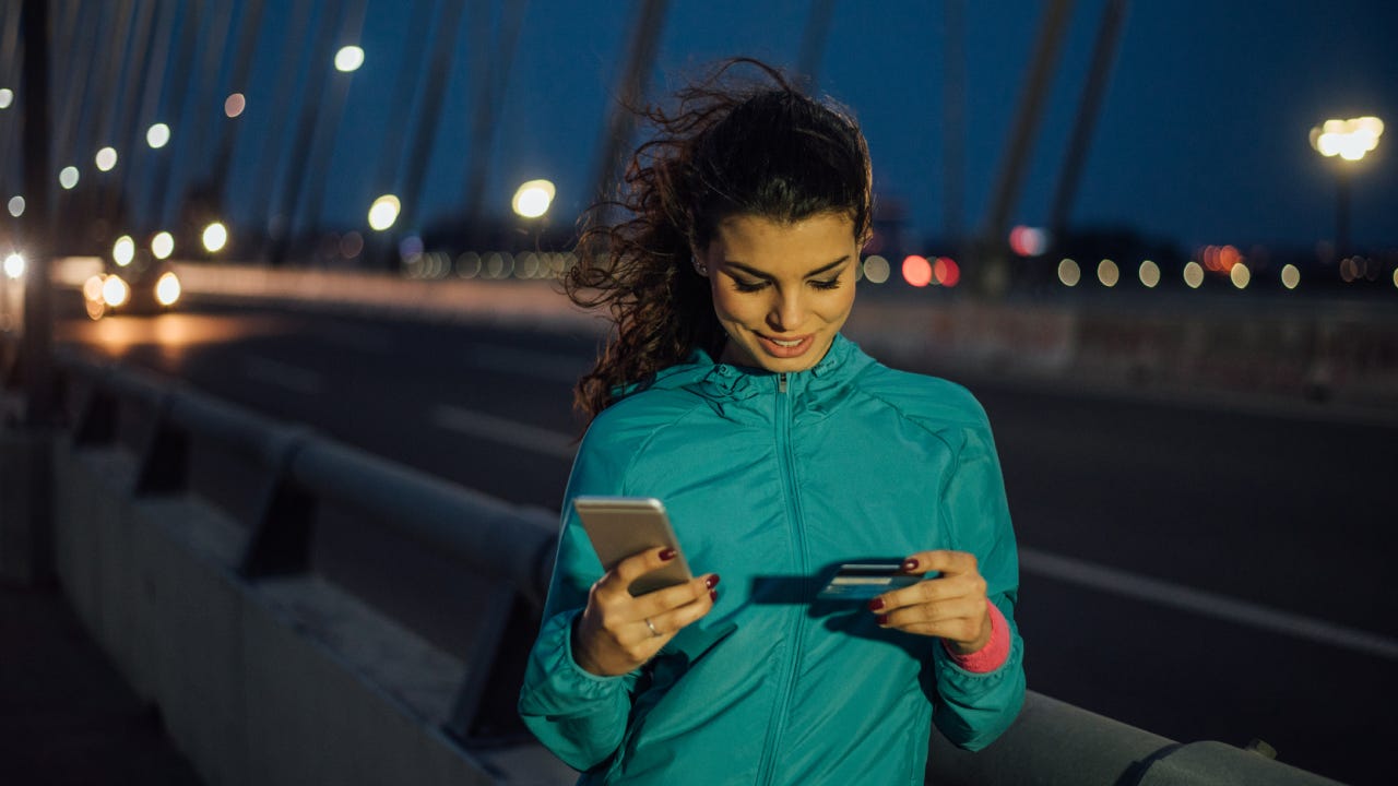 Athletic woman using credit card and mobile phone