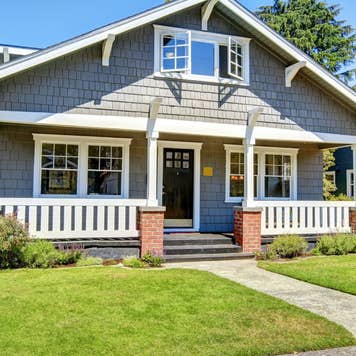 Clapboard siding house exterior. Large entance porch with brick trim and white railings