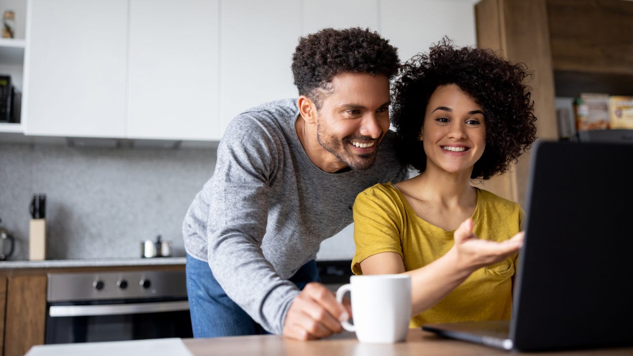 Couple at home making a reservation online using their laptop