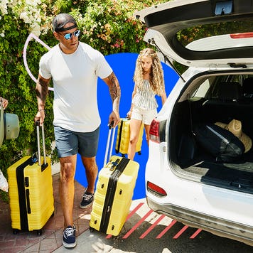 A family loads luggage into their car's trunk