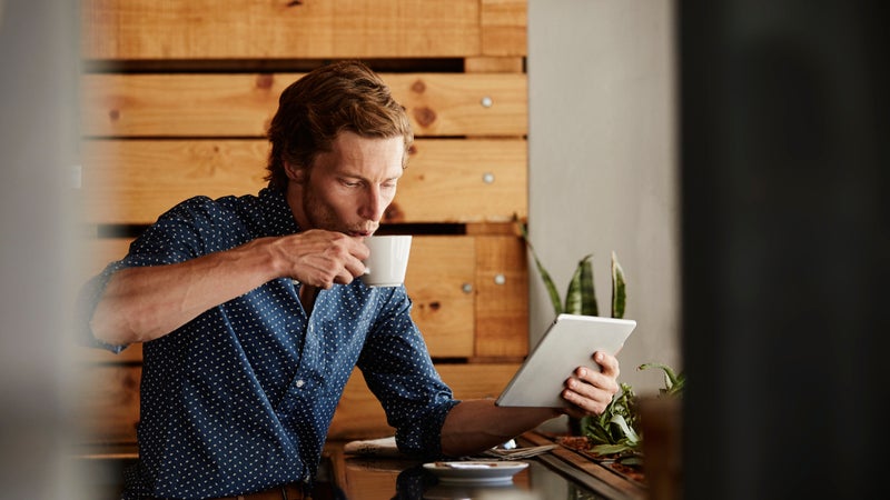 Man using tablet PC while having coffee at cafe
