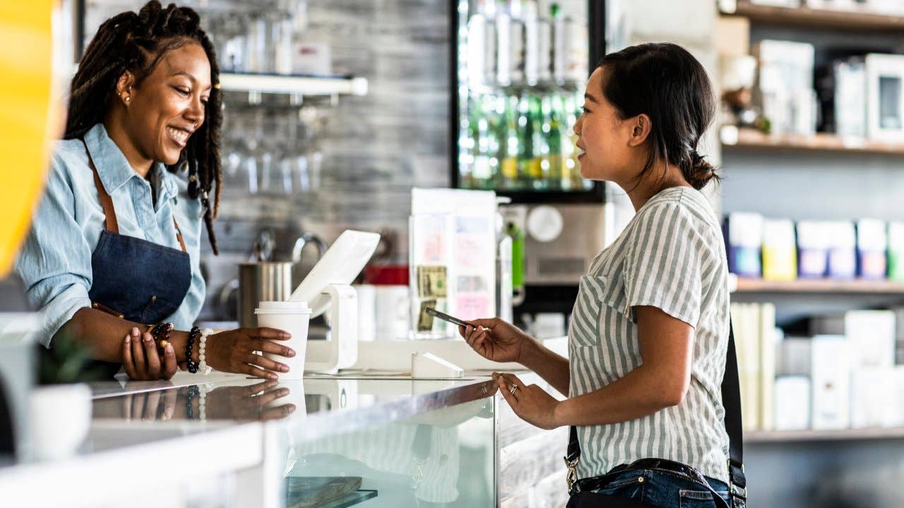 Young woman paying for coffee with credit card