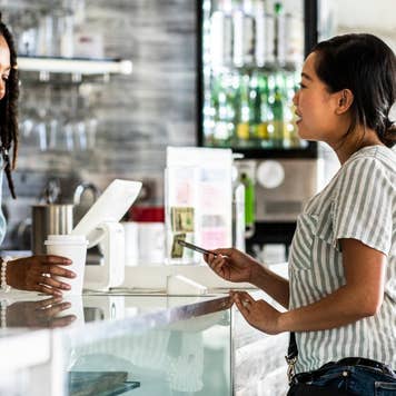 Young woman paying for coffee with credit card
