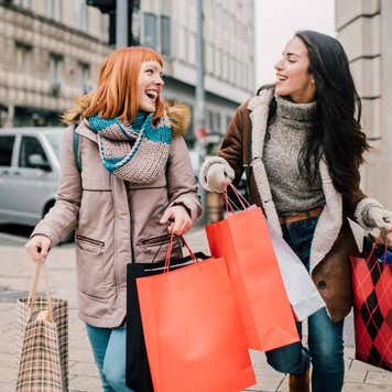 Happy two girls holding bunch of shopping bags